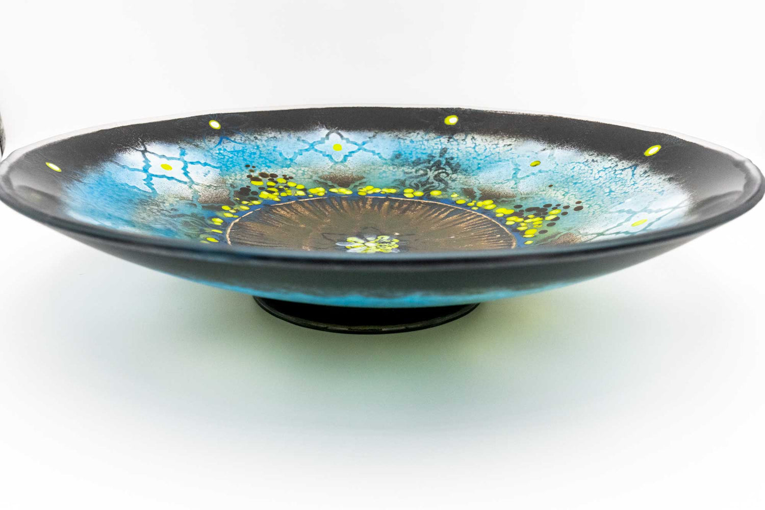 Large glass bowl decorated with an abstract pattern. Dominate colors are blue, black, and chartreuse.
